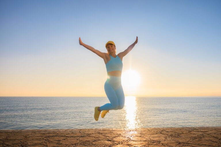 mujer feliz saltando en la playa