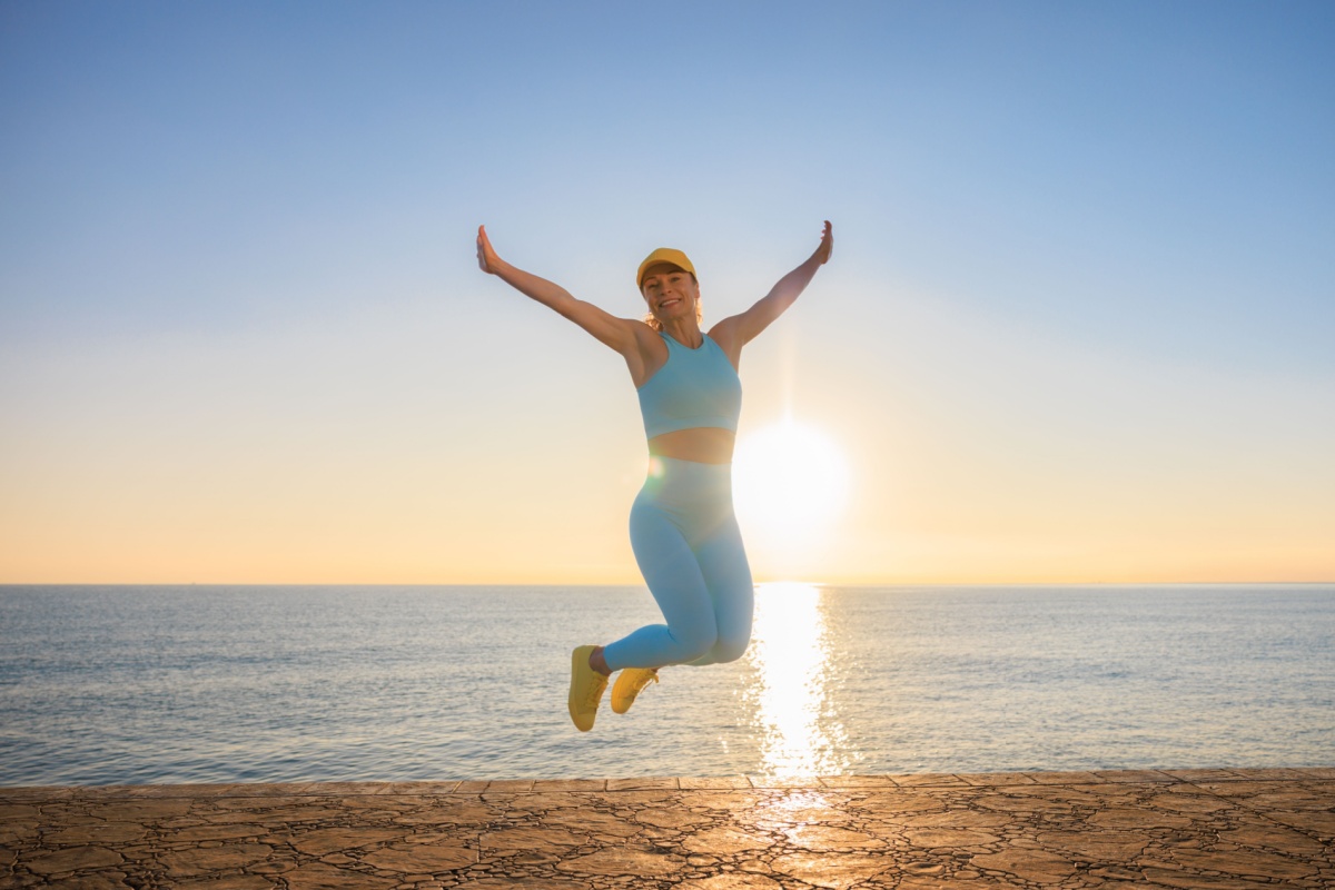 mujer feliz saltando en la playa