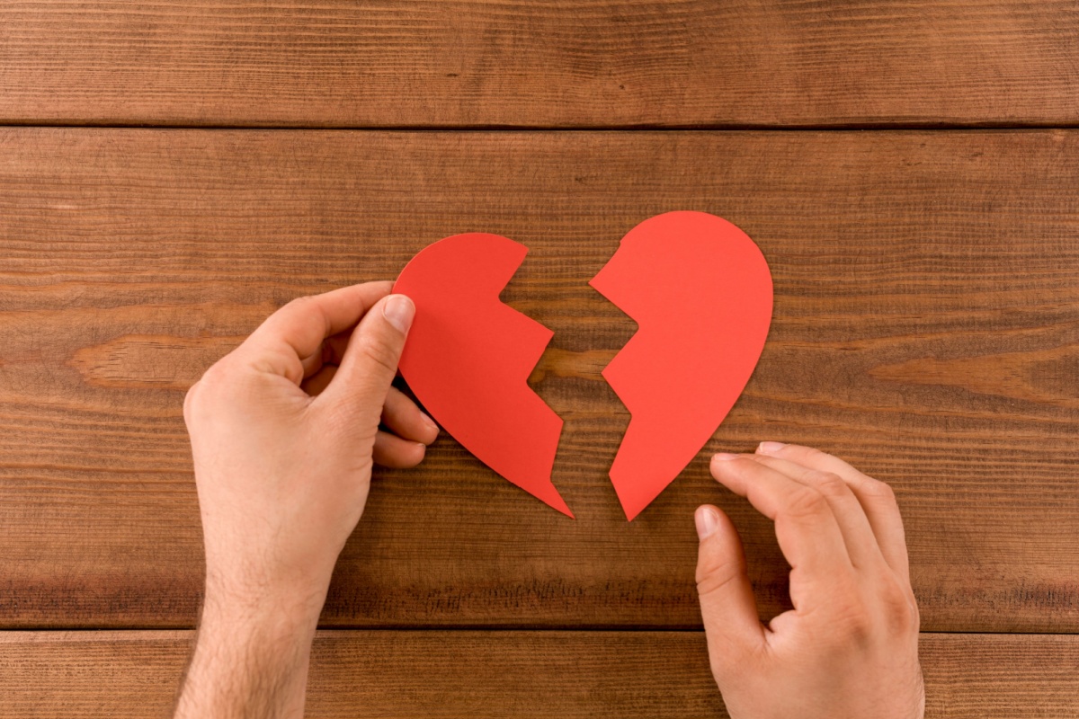 manos sosteniendo un corazón de papel roto