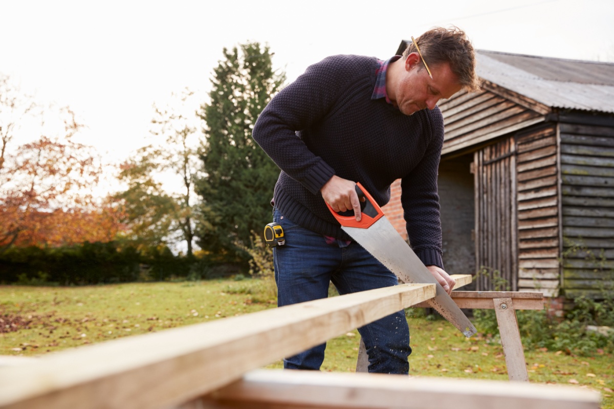 man sawing wood outdoors
