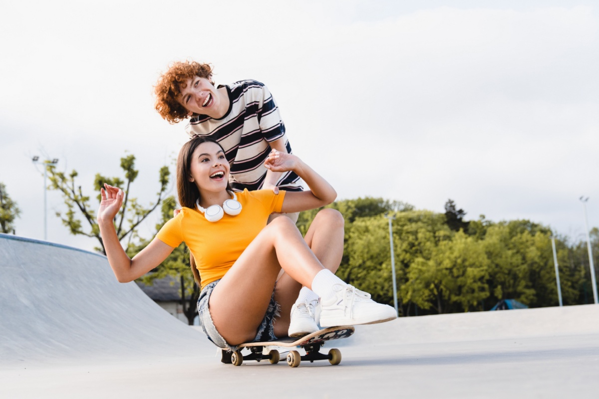 two teens laughing while skatebording
