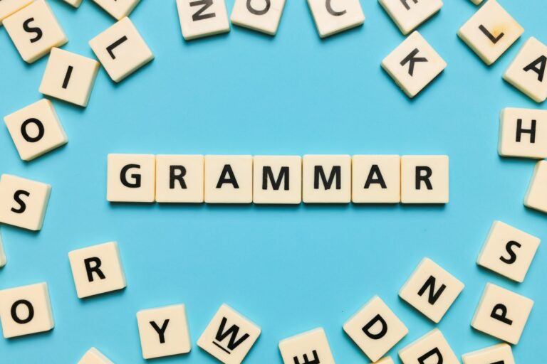 wood letters creating the word grammar on a light blue background
