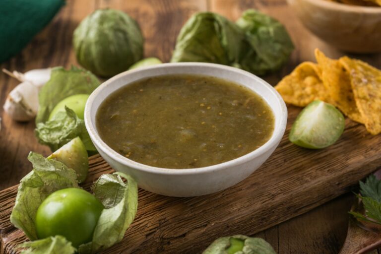 a bowl of salsa verde with tomatillos around it
