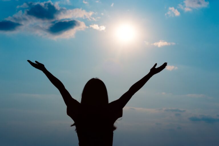 silueta de mujer levantando los brazos al cielo