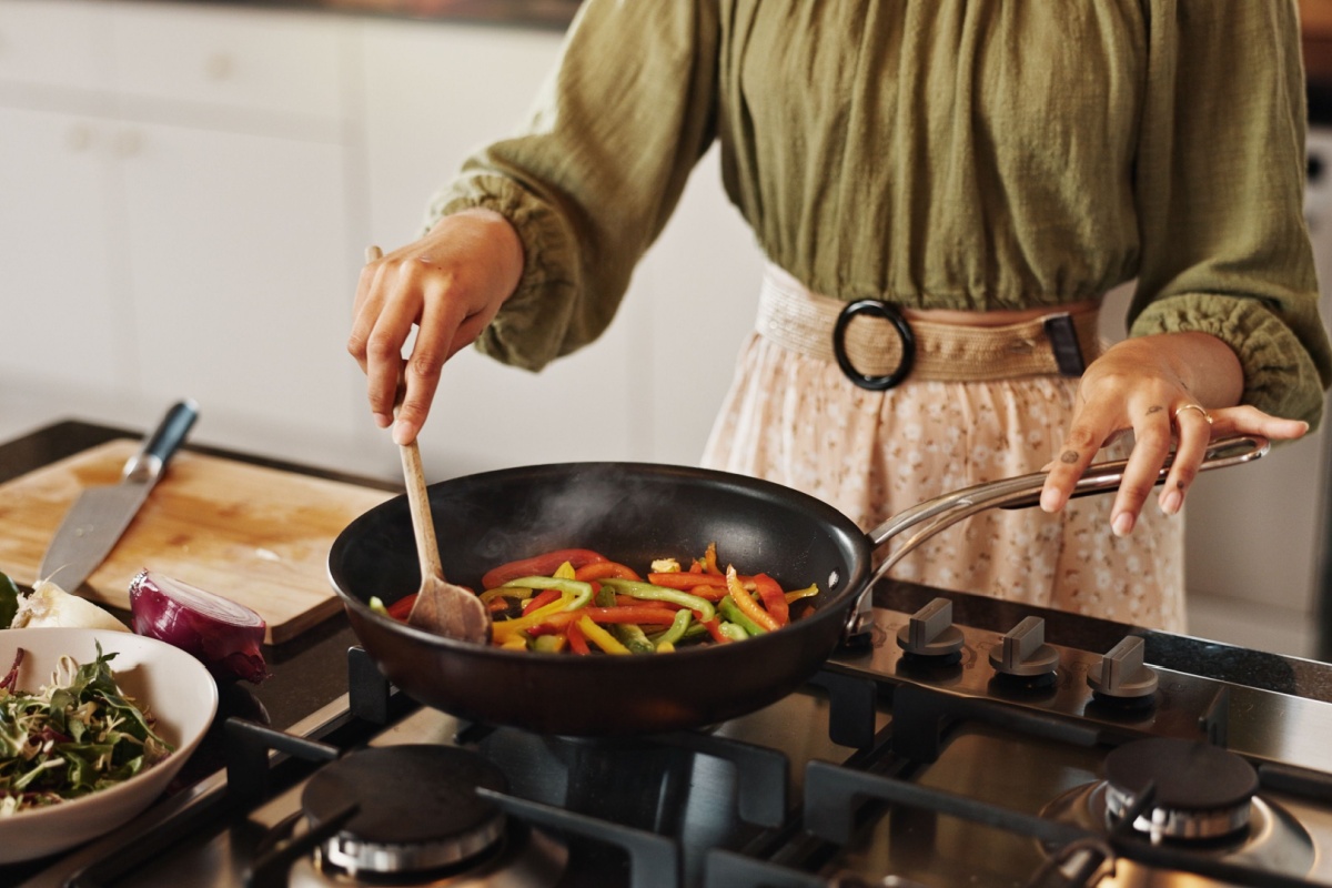 woman cooking veggies in a pan
