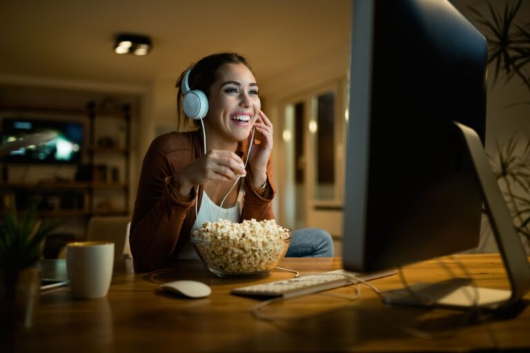 woman watching a show in her computer while eating popcorn