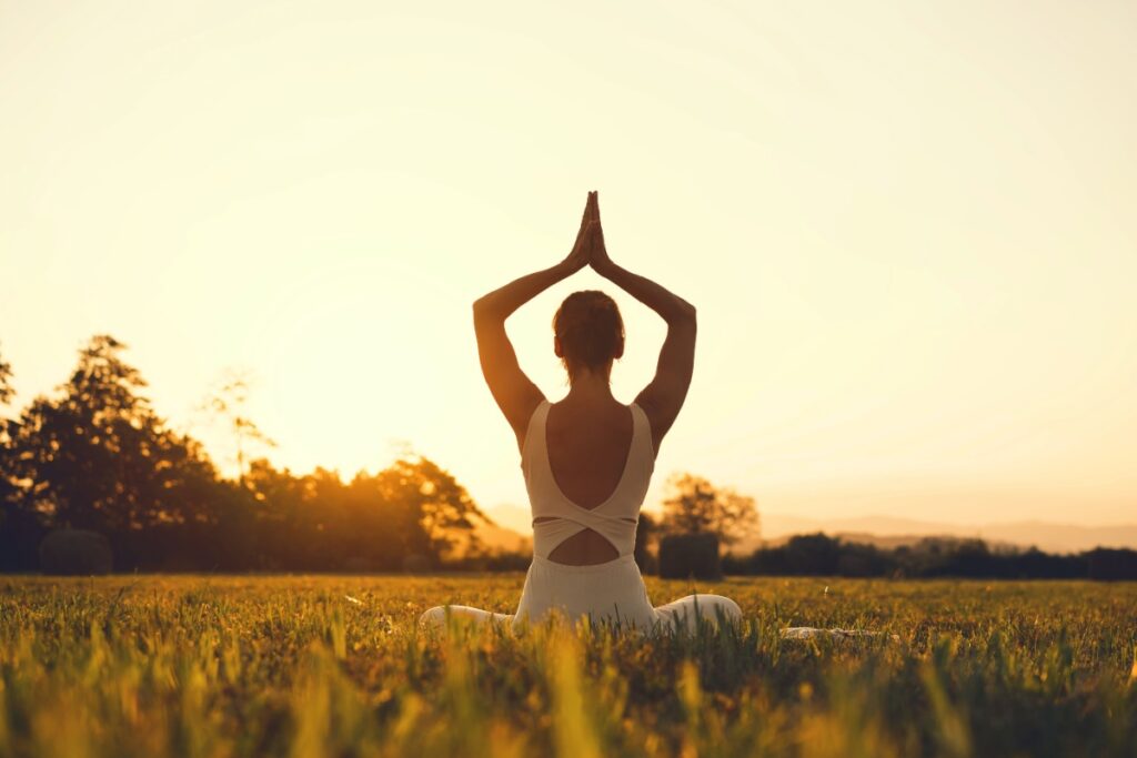woman practicing yoga at sunset