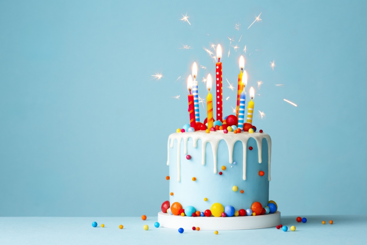pastel de cumpleaños con varias velas sobre fondo celeste