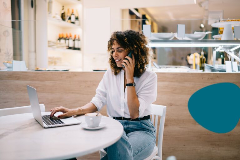 woman working in her laptop while talking in her phone