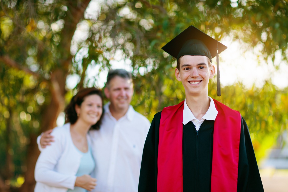 graduated teen and his parents behind him