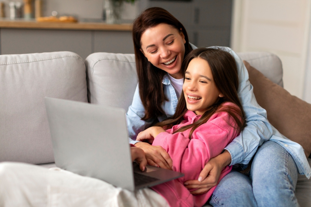 madre e hija en el sofá mirando algo en la laptop