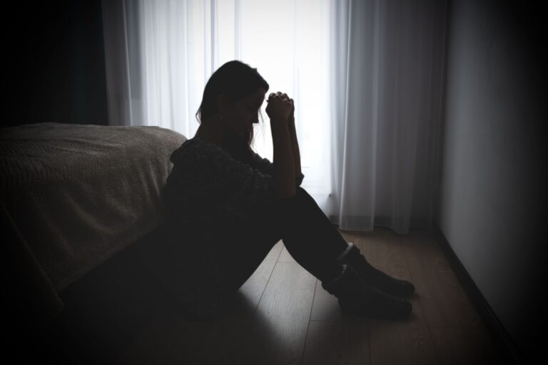 sad woman sitting on the floor in a dark room