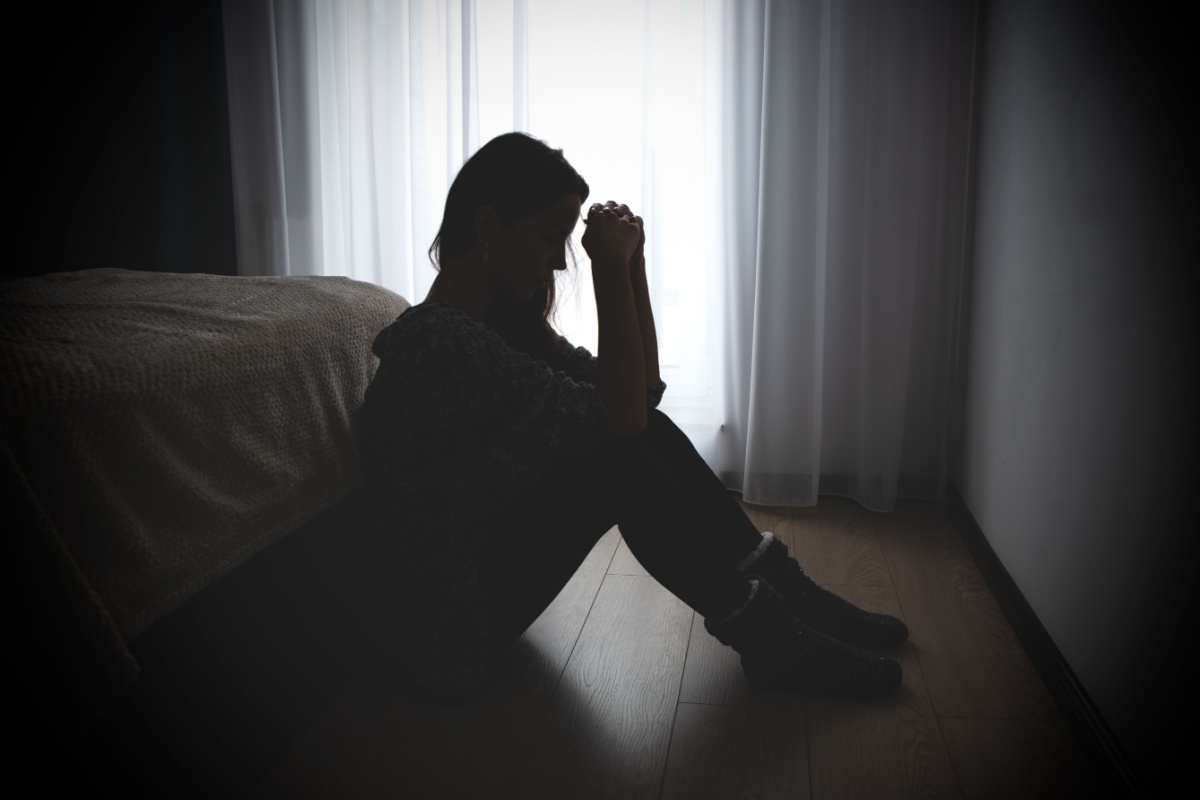 sad woman sitting on the floor in a dark room