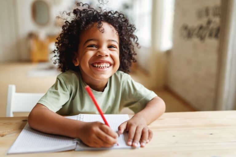 niño sonriente escribiendo a mano