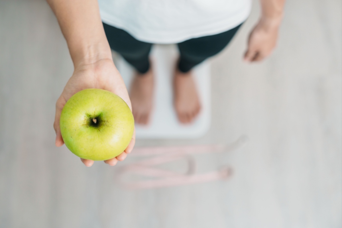mujer en una balanza, sosteniendo una manzana verde