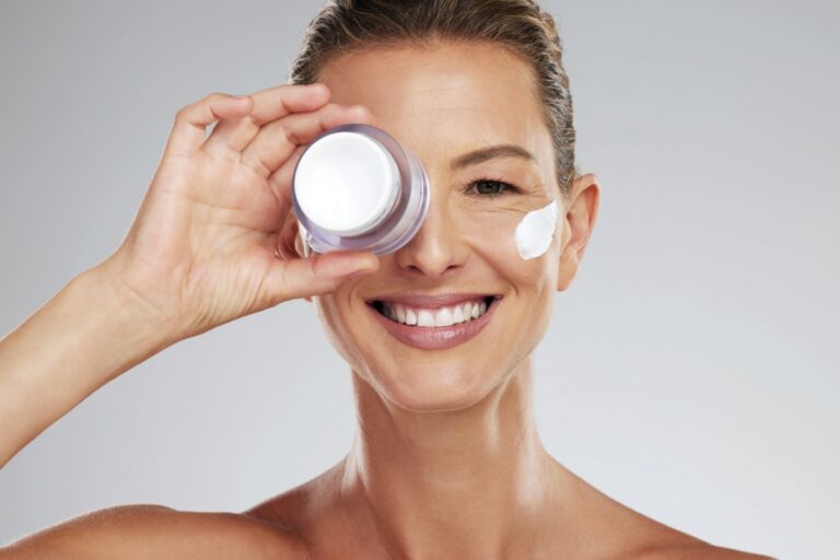 mujer con pote crema frente a uno de sus ojos