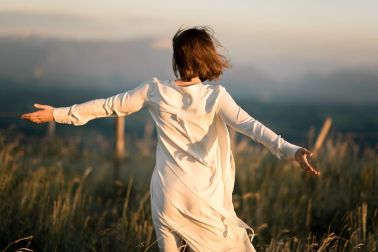mujer de espalda con los brazos abiertos en la naturaleza