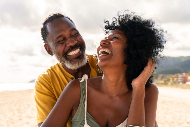 pareja de mediana edad en la playa sonriendo