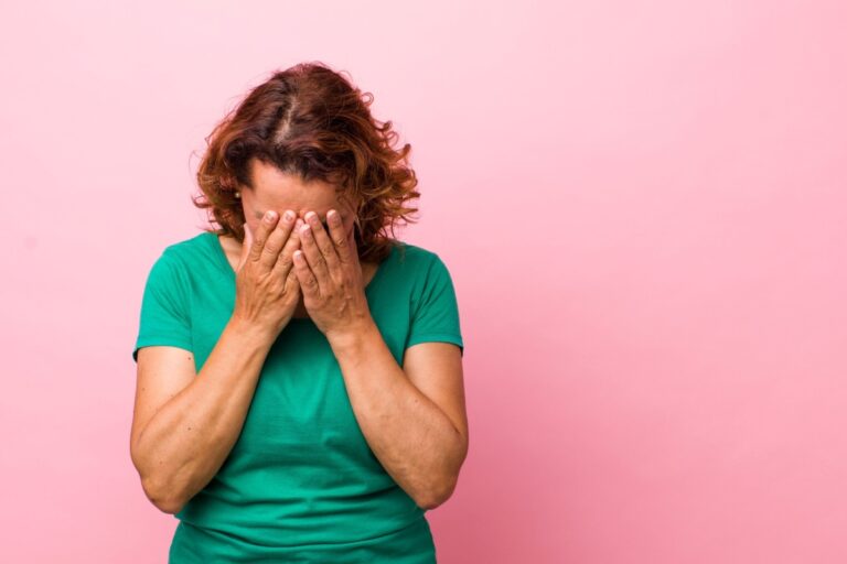 midlife woman holding her head with her hands