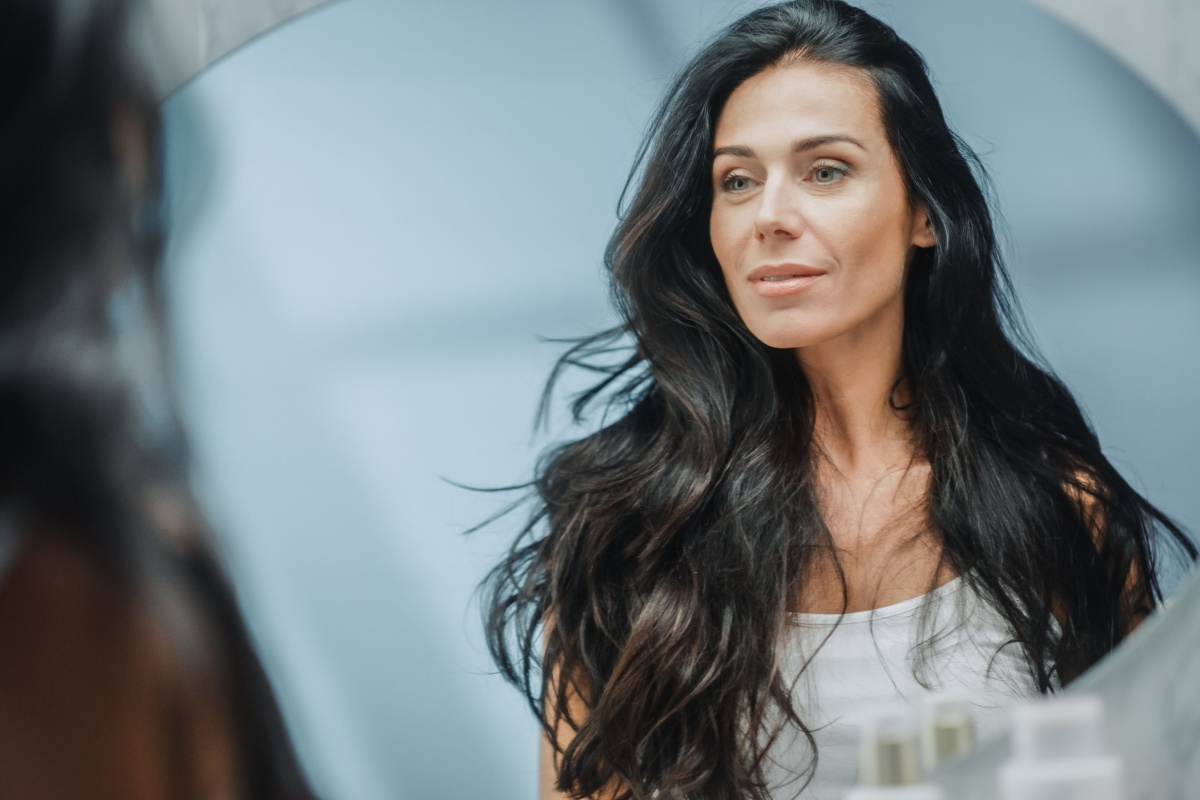 middle aged woman with long hair in front of a mirror