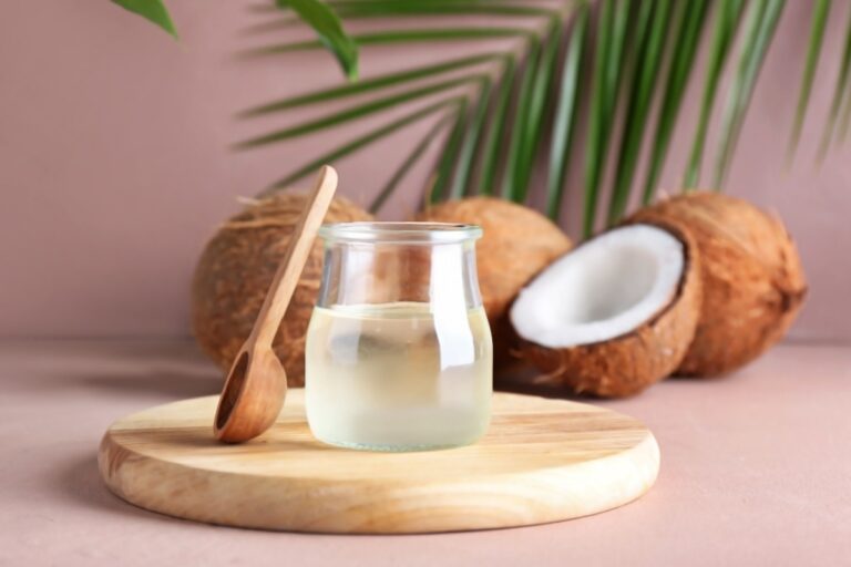 un frasco con aceite de coco y cocos detrás