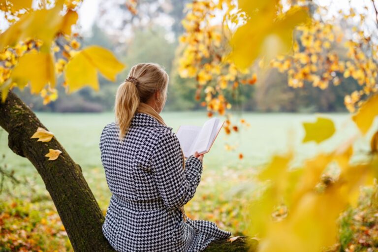 mujer sentada en un árbol leyendo un libro
