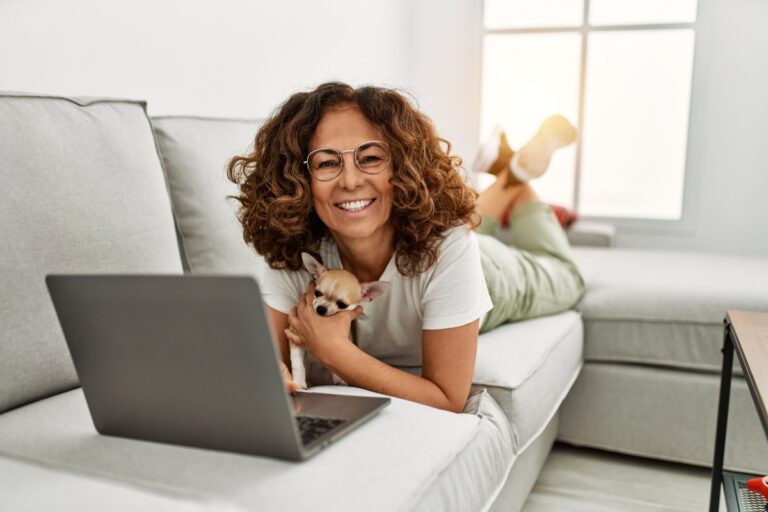 woman with a dog checking her laptop in the couch