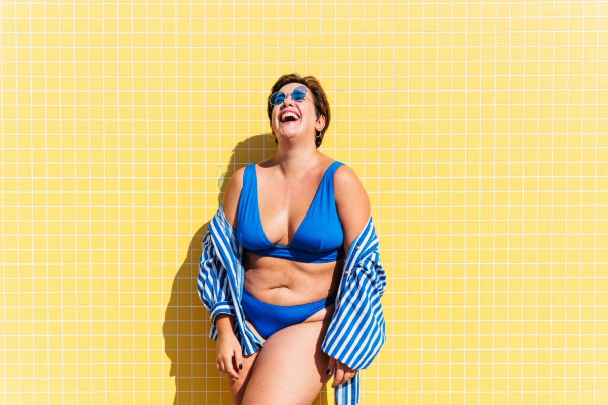 mujer de mediana edad en bikini azul sobre fondo amarillo