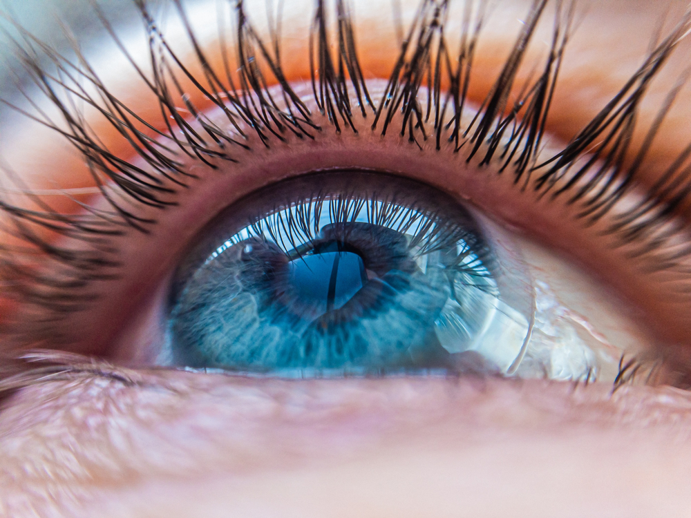 Close up photo from a low angle of a person's blue eye with a contact lens.