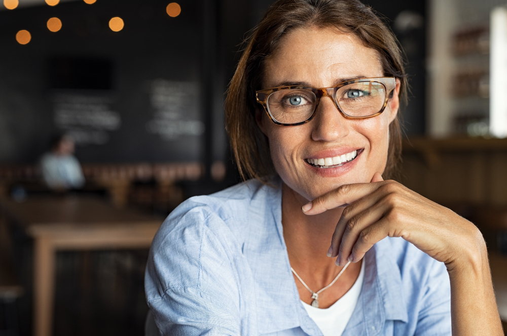 Portrait of a middle aged, smiling woman wearing tortoise shell glasses.