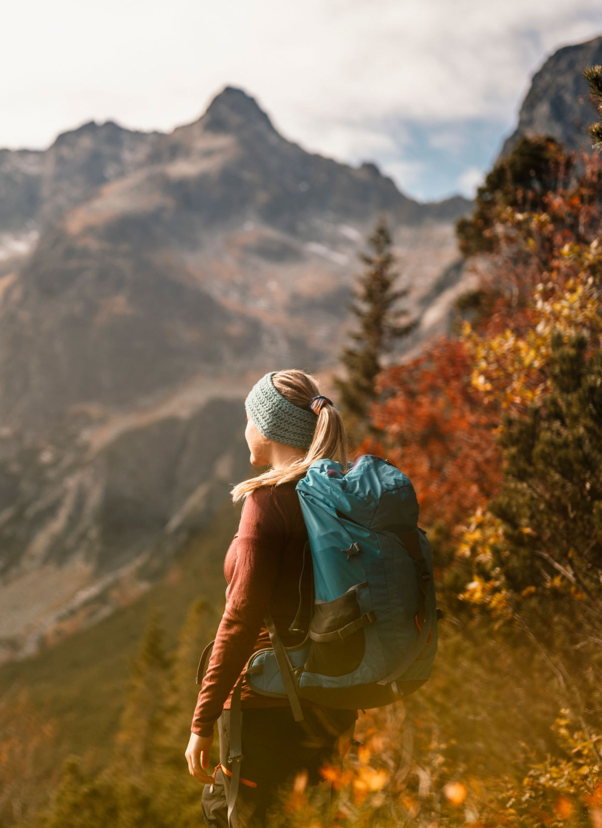 A woman with a backpack hiking in the mountains.